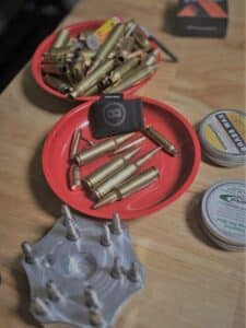 Bullets and gun cleaning supplies in red trays on a wooden table.