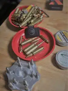 Bullets and gun cleaning supplies in red trays on a wooden table.